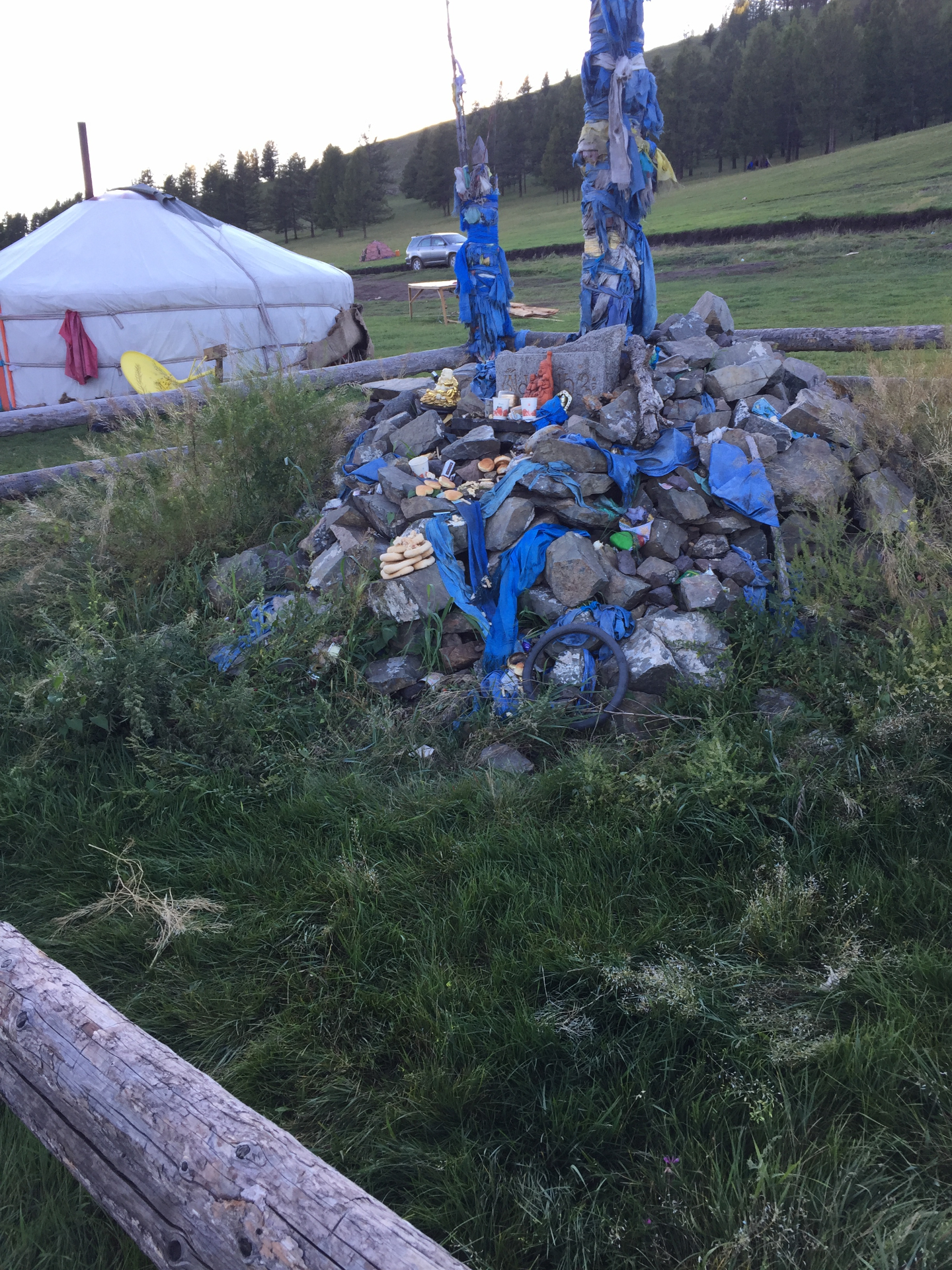 Asher pole and stone altar with offerings near a yurt